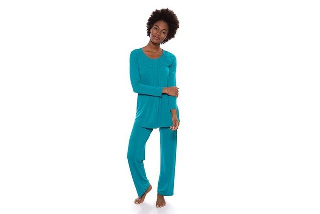 A person wearing teal loungewear stands casually, arms relaxed, against a plain white background.
