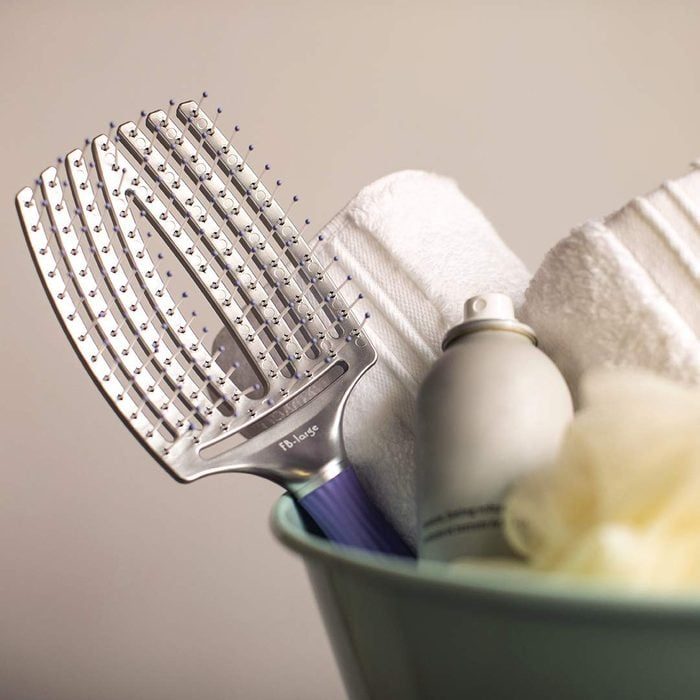 Vent hairbrush rests in a bowl with towels, a spray bottle, and a bath sponge.