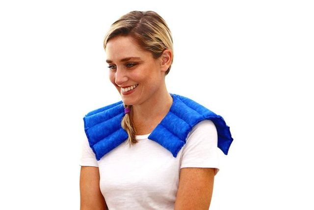 A person wears a blue shoulder wrap, smiling in a relaxed pose, against a plain white background.