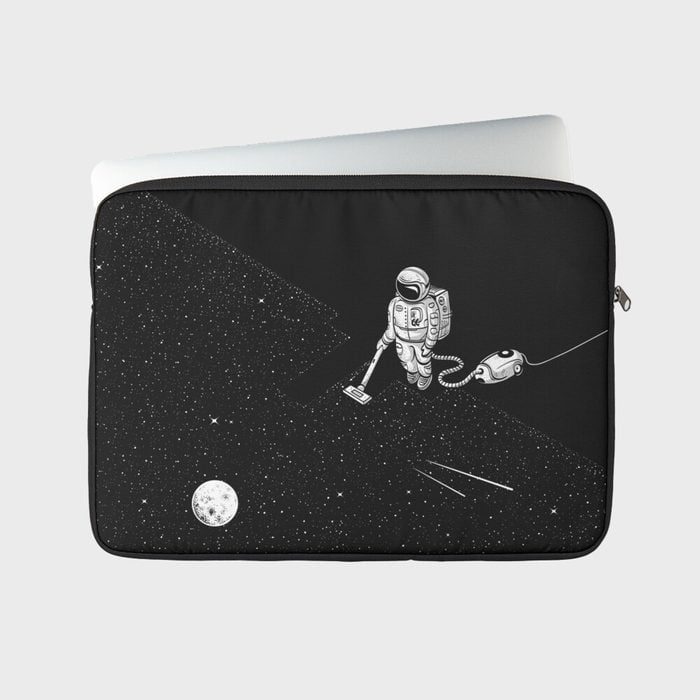 Astronaut vacuums stars in space scene on a black laptop sleeve; moon visible, creating a whimsical, cosmic cleaning theme.