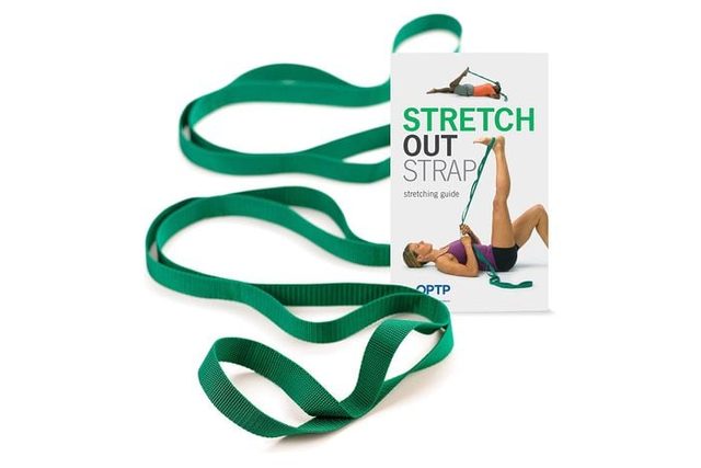 Green stretching strap lies extended next to a leaflet showing a person using it for leg exercises. Text includes 
