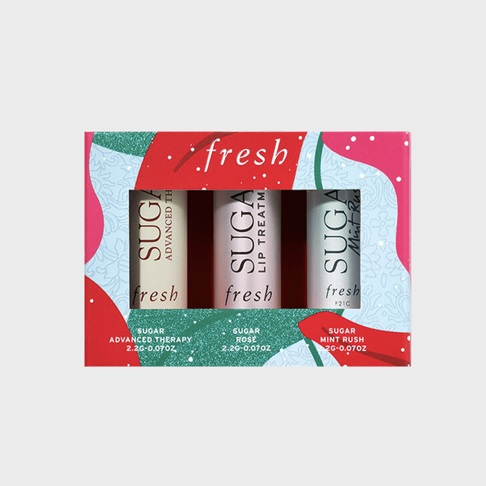 Three lip balm tubes sit in a colorful, festive box marked 