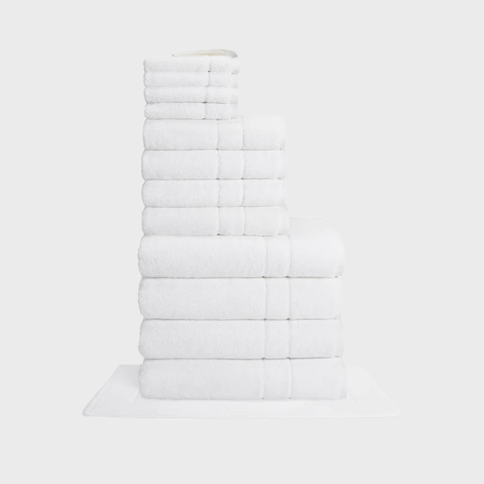 Stacked white towels, arranged neatly, form a pyramid-like structure on a white surface.