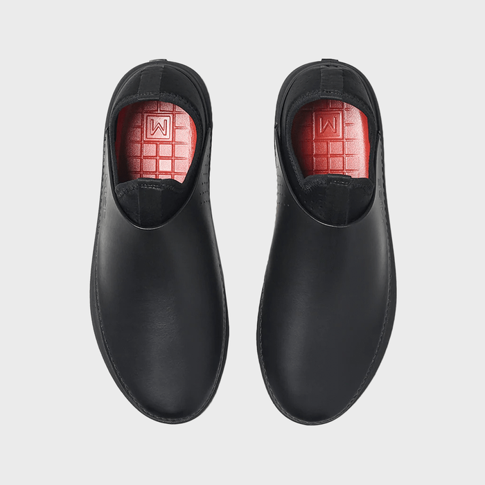 Black shoes rest side by side, revealing red insoles with grid patterns and an 