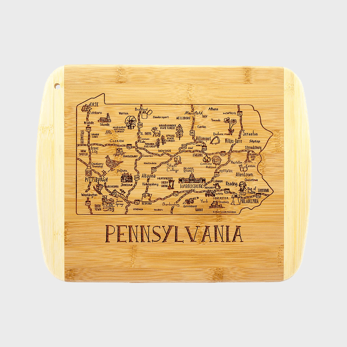 Wooden cutting board features an engraved map of Pennsylvania, showcasing cities and landmarks, framed by a plain background. Text: 