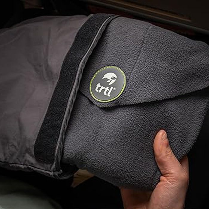 Hand holding a folded gray travel pillow with 