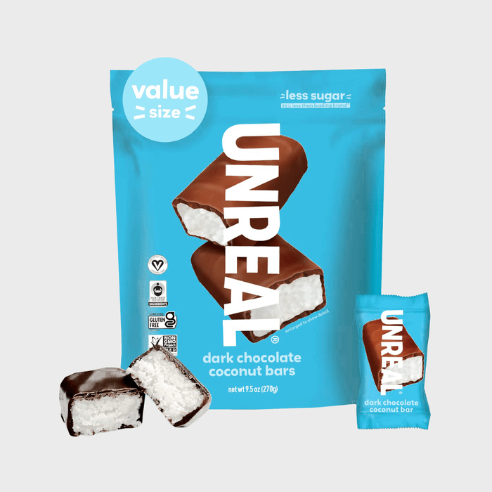 Bag of dark chocolate coconut bars with smaller wrapped bar, shown against a blue background. Text includes â€œUNREALâ€ and â€œvalue size.â€