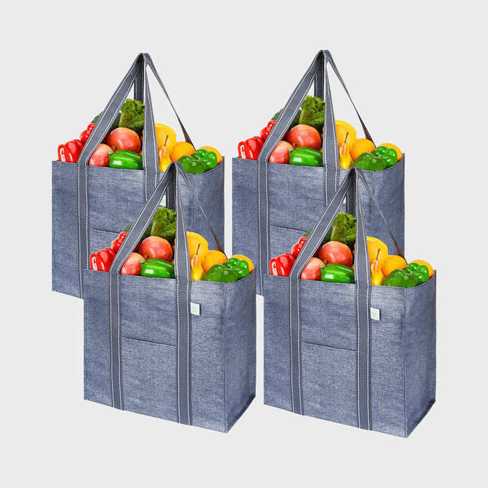 Four gray reusable grocery bags filled with colorful fruits and vegetables, arranged side by side against a plain white background.