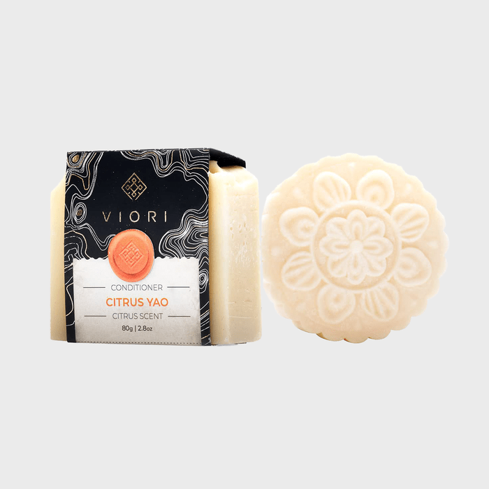 Bar soap rests next to a boxed conditioner with intricate floral design; packaging reads 