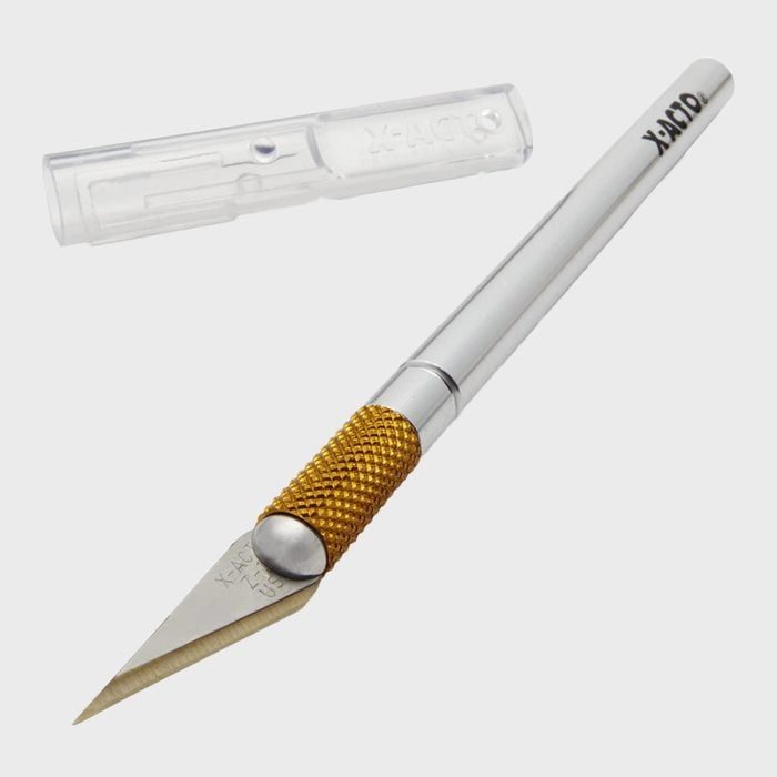 Precision knife with a silver handle and gold grip, lies on a light surface. Removable plastic blade cover marked 