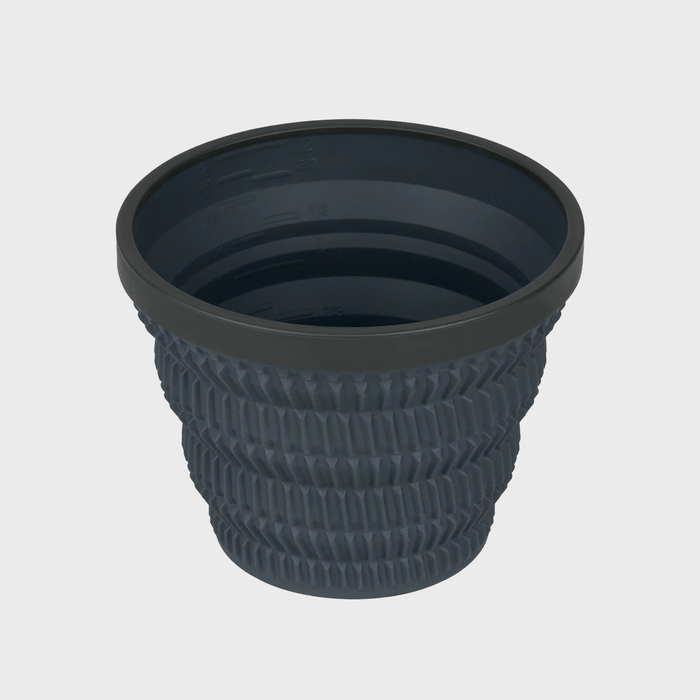 Collapsible dark gray cup with ribbed texture; measurements marked inside. Set against a plain light background.