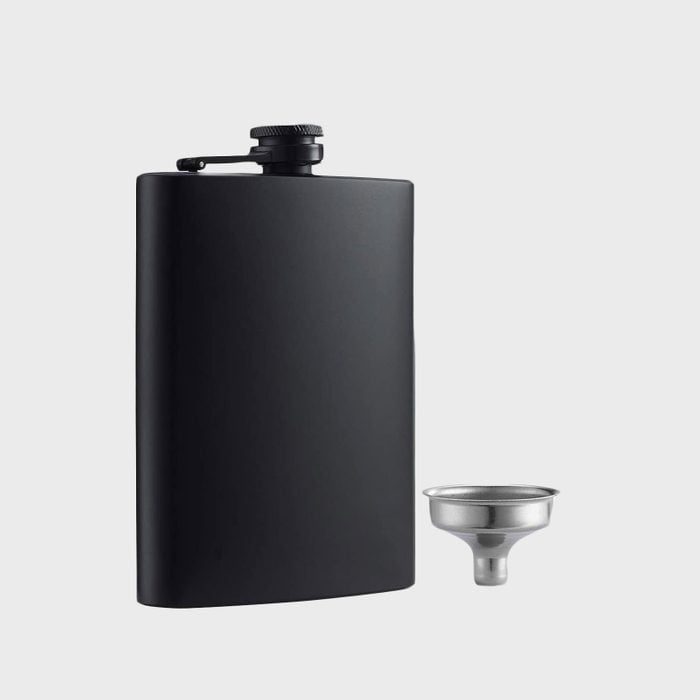 A black flask stands upright with a small metal funnel beside it on a plain gray background.
