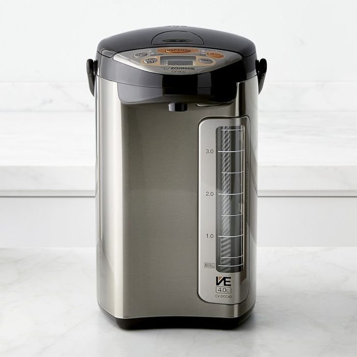Stainless steel water boiler, standing idle, on a white kitchen countertop.