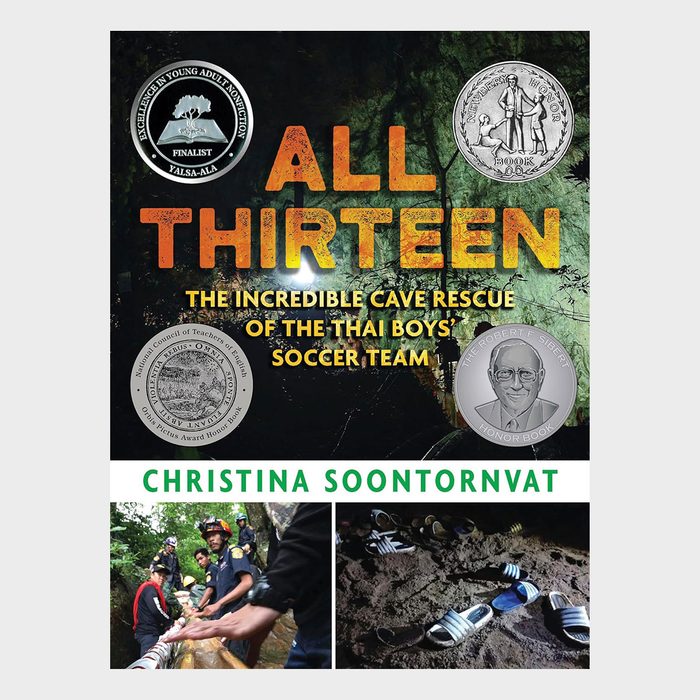 Book cover shows a cave with rescuers, featuring text: â€œALL THIRTEEN: THE INCREDIBLE CAVE RESCUE OF THE THAI BOYSâ€™ SOCCER TEAMâ€ by Christina Soontornvat. Awards depicted.