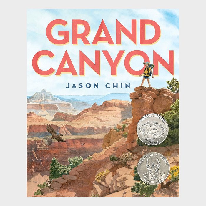 Book cover features hiker standing on a rock, overlooking the Grand Canyon, with two award medals depicted below. Text reads 