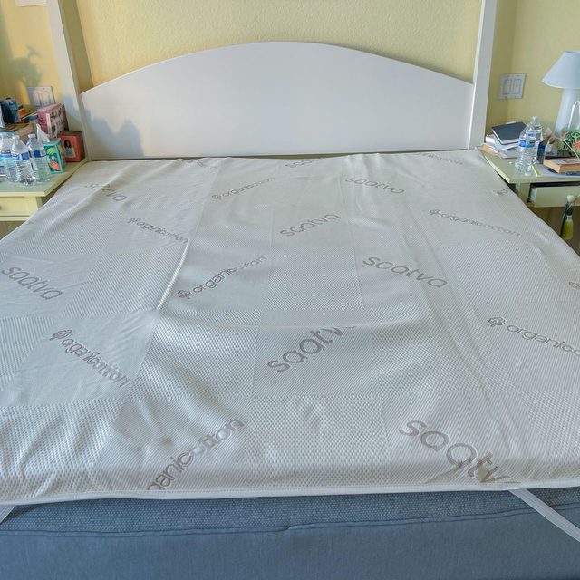 Mattress topper lies on bed; branded 