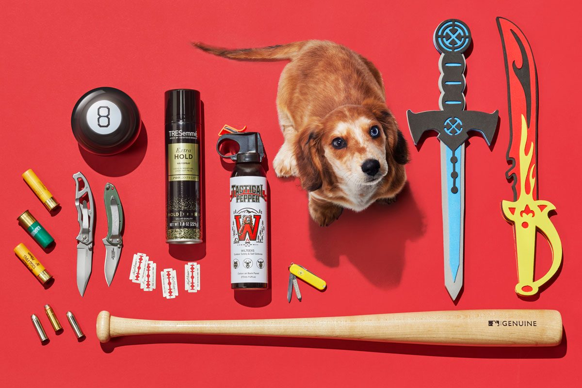 array of items banned from carryon luggage arranged on a red background