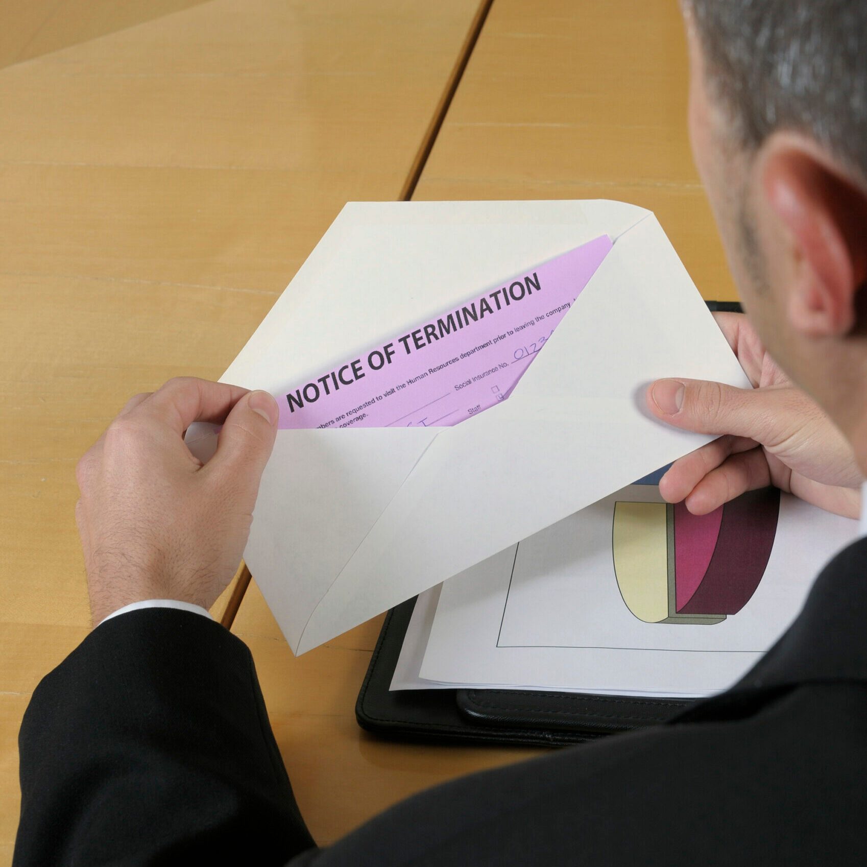 Man opening an envelope containing pink notice of termination