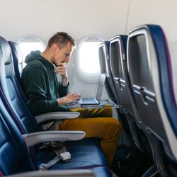 Man using a laptop in an airplane seat