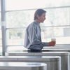 Businessman holding drink walking through office entrance barriers