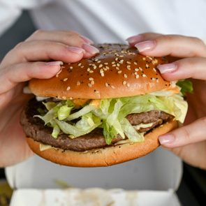 Two hands holding a McDonald's hamburger
