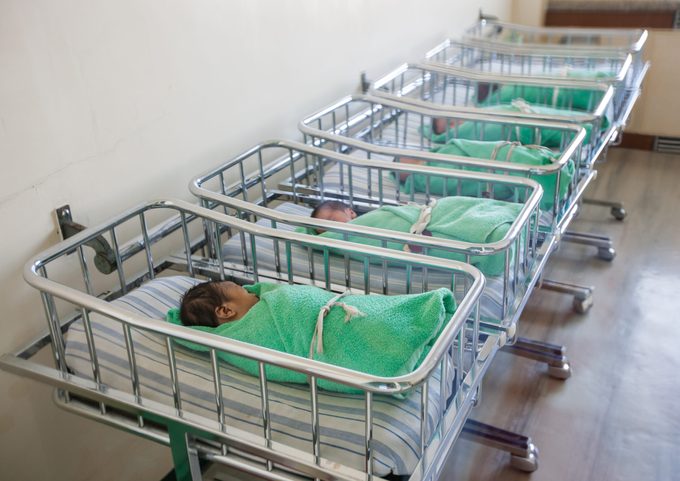 five newborn babies wrapped in green blankets in a maternity ward