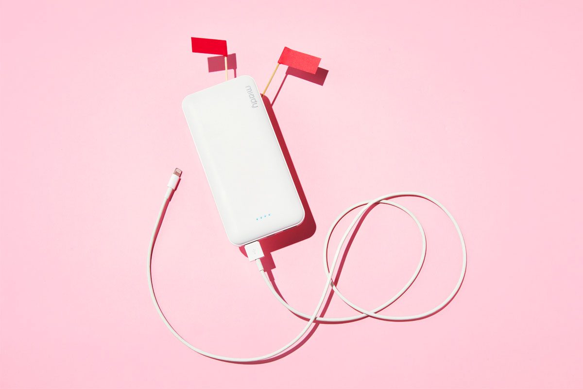 external lithium power bank battery with red flags against a pink background