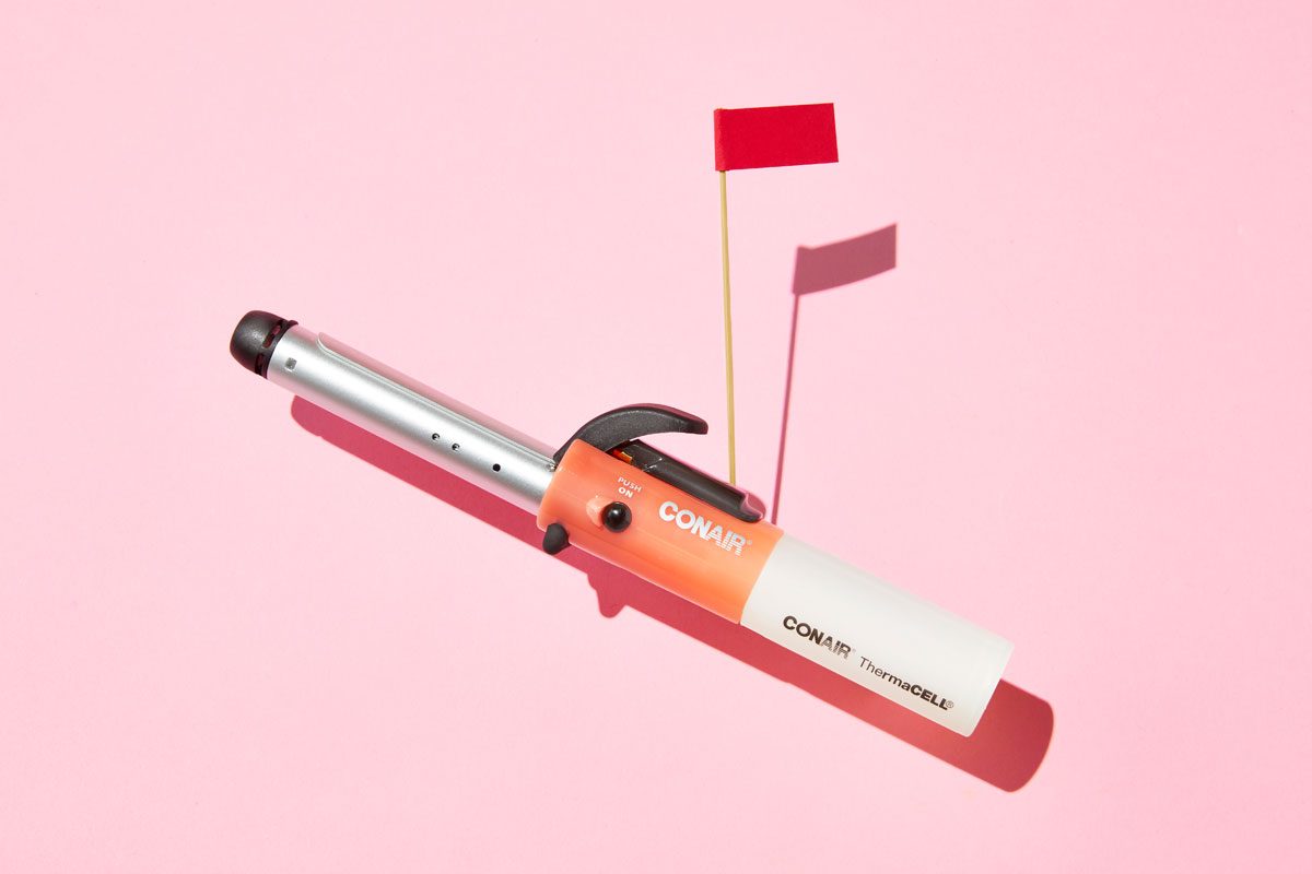 cordless curling iron with red flag against pink background