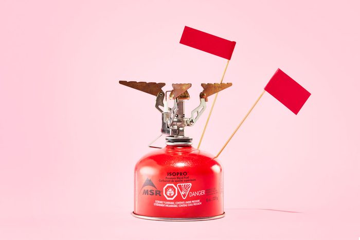 propane camp stove with red flags against a pink background