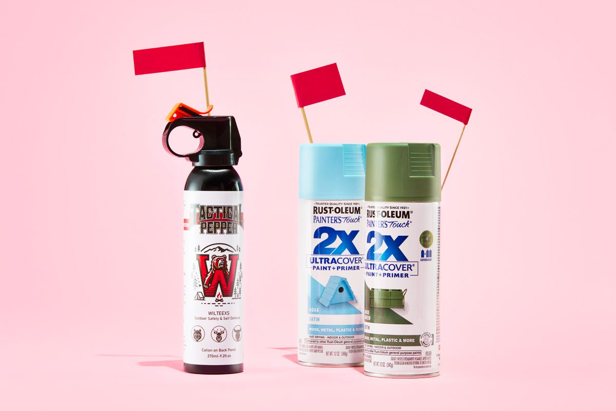 aerosol cans of bear spray and spray paint with red flags against a pink background