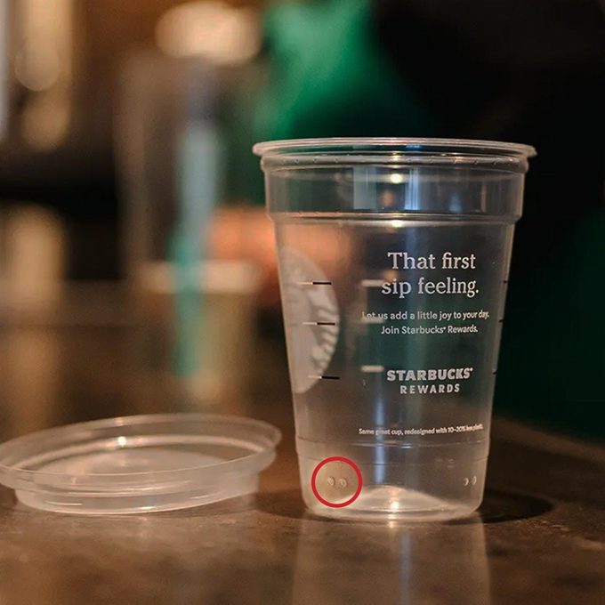Starbucks iced cup with a lid next to it, with two raised dots on the bottom of the cup. Dots are circled in red