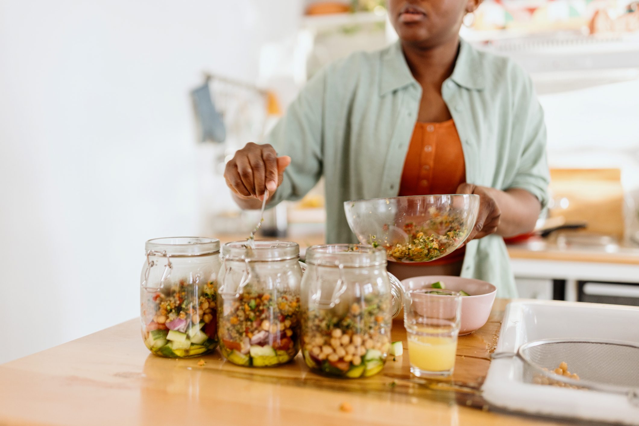 Woman meal prepping a salad into three jars