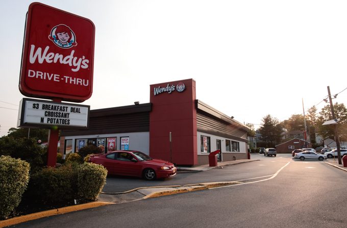 exterior of a Wendy's with a red car exiting the drive thru