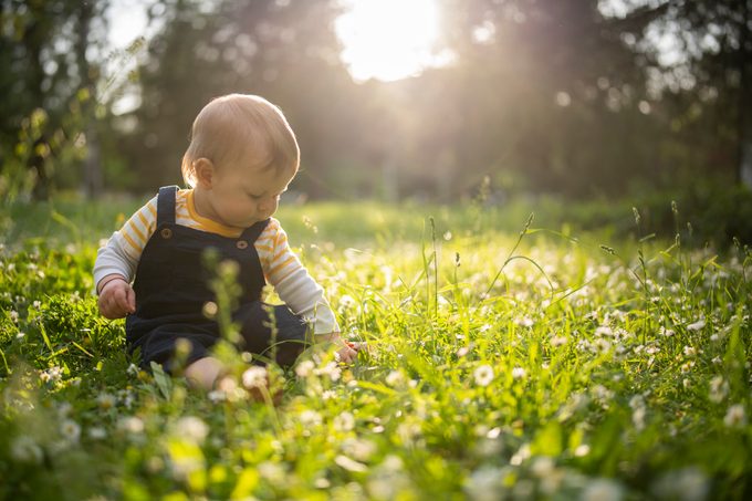 Baby boy sitting in the grass in a public park.