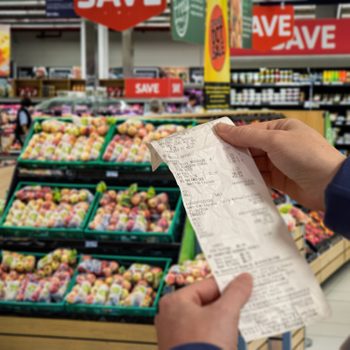 Woman shopping at a grocery store and checking her receipt