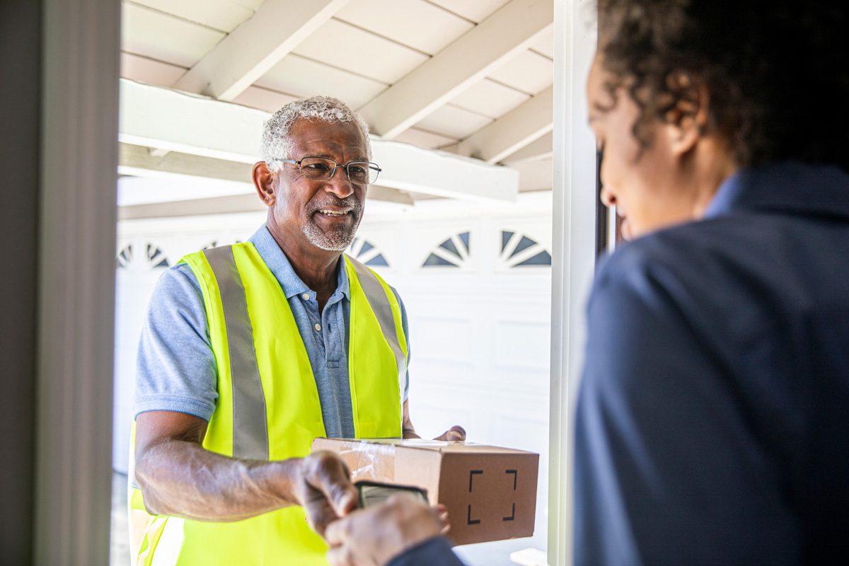 A senior black man delivers a package to a woman