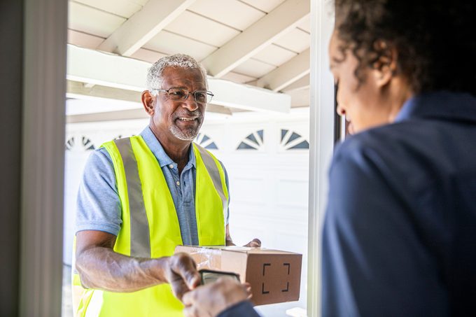 A senior black man delivers a package to a woman
