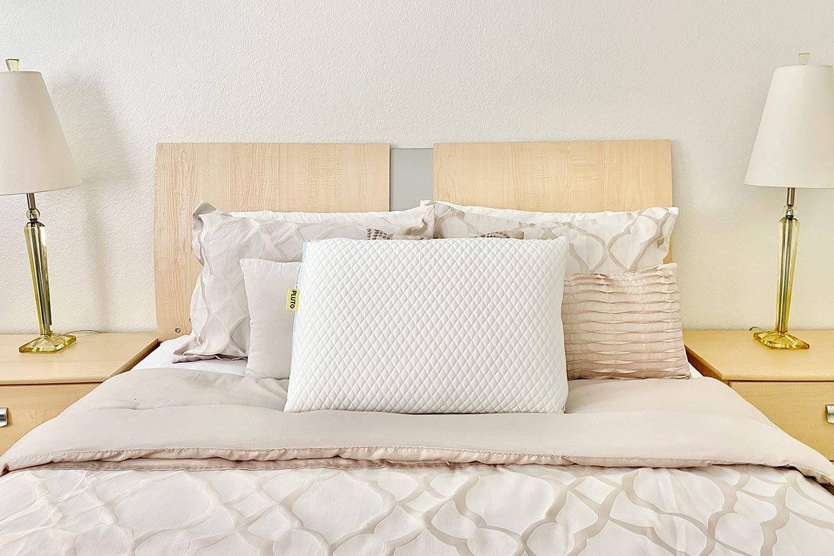 A neatly made bed with set of Pluto pillow placed at the center.