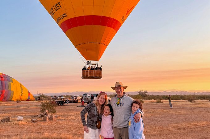 family posing in front of hot air balloon