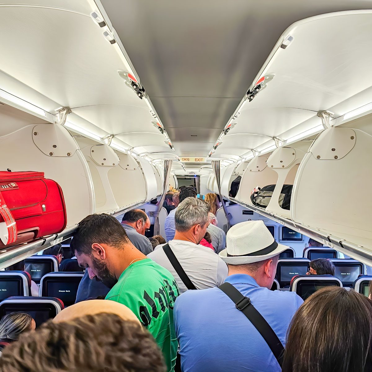 Passengers Standing In Airplane For Deboarding