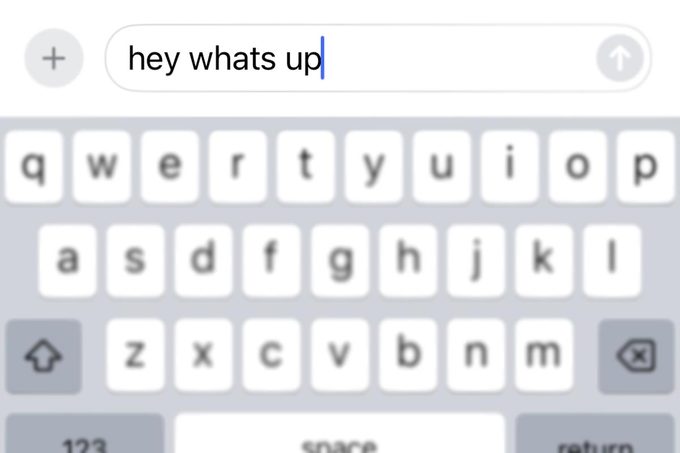 iPhone keyboard with a "hey whats up" text about to be sent
