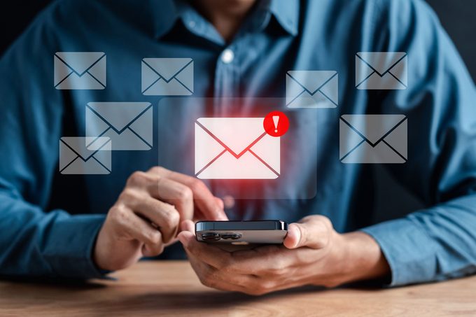 man holding phone with email alerts hovering around