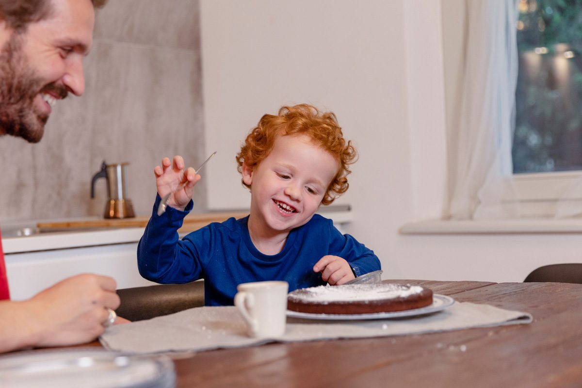 father and kid looking at chocolate cake on table