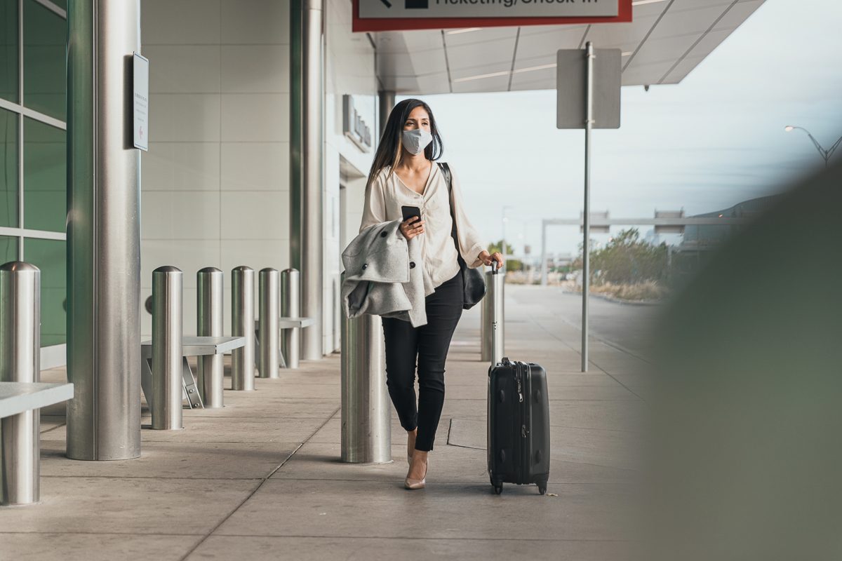 woman wearing face mask walking at airport terminal