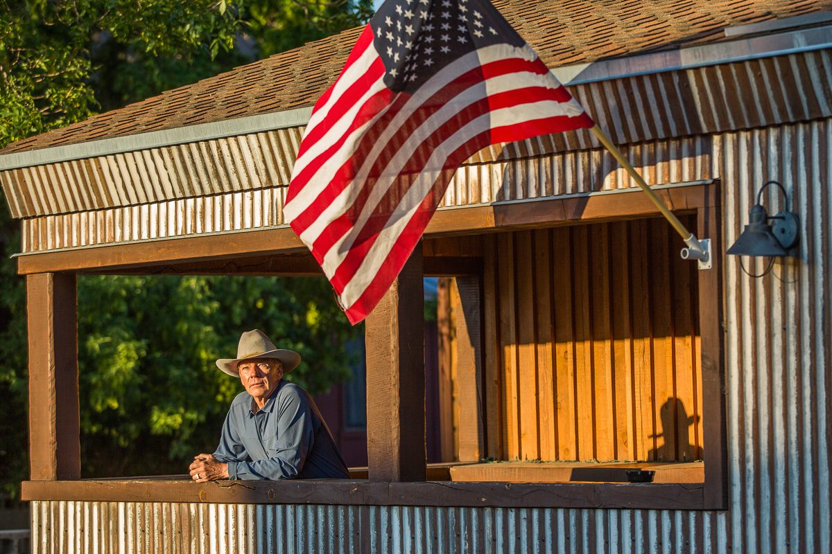 old man on porch with American flag