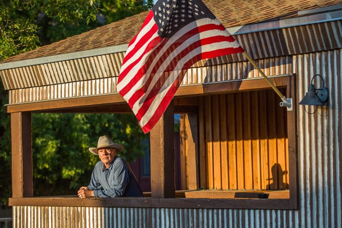 old man on porch with American flag