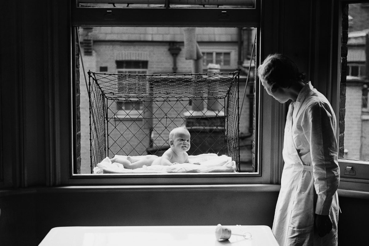 nanny looking at baby suspended in a wire cage