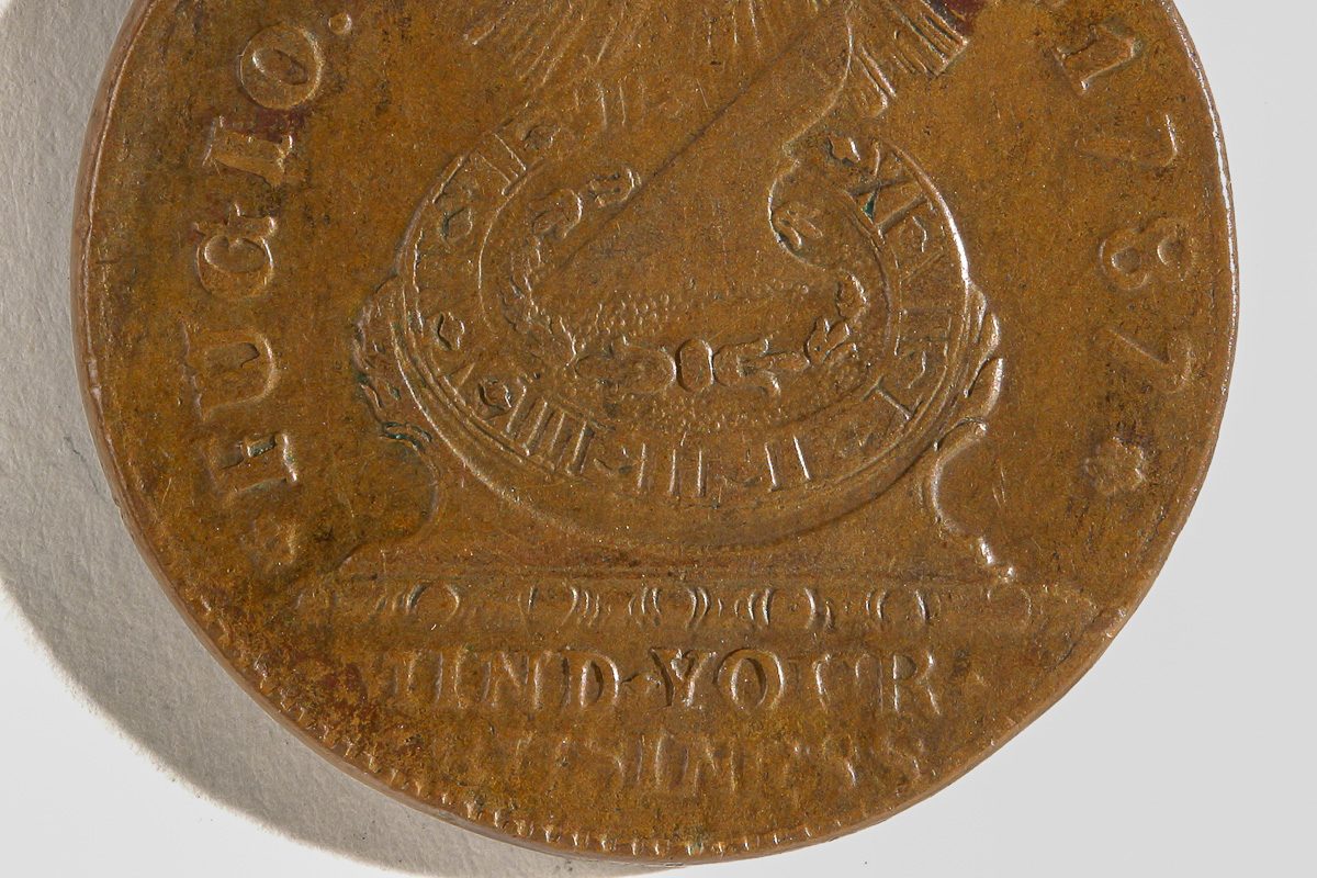 old coin with "mind your business" inscription