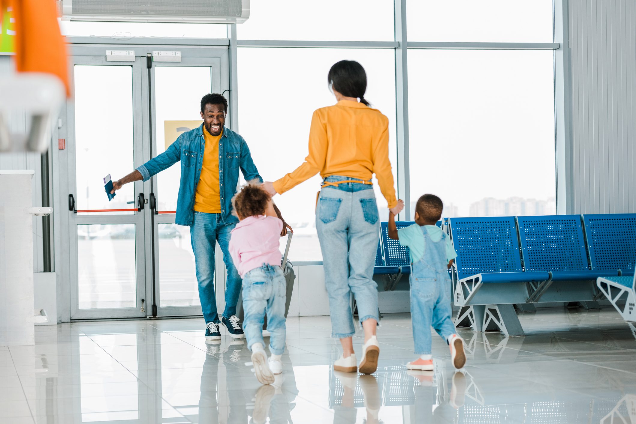 Mother with children receiving happy african american man at airport
