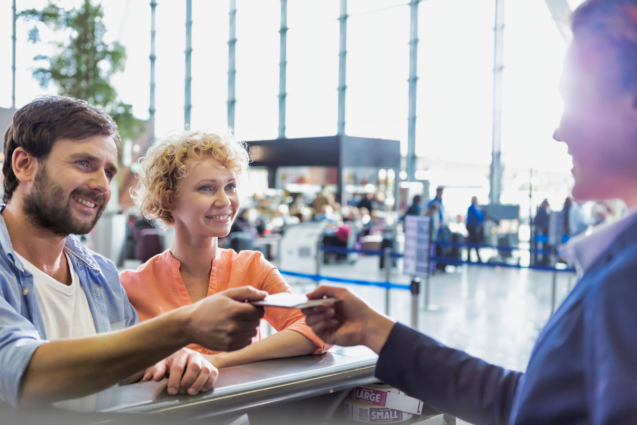 Portrait of man giving passport to passenger service agent to get his boarding pass in airport